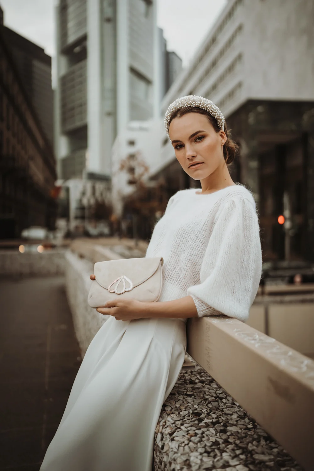 Braut trägt handgestrickten weißen Brautpullover „Your Love Is King“ aus der Jubiläumskollektion, kombiniert mit einem langen Rock und Perlen-Stirnband, fotografiert in Frankfurt.