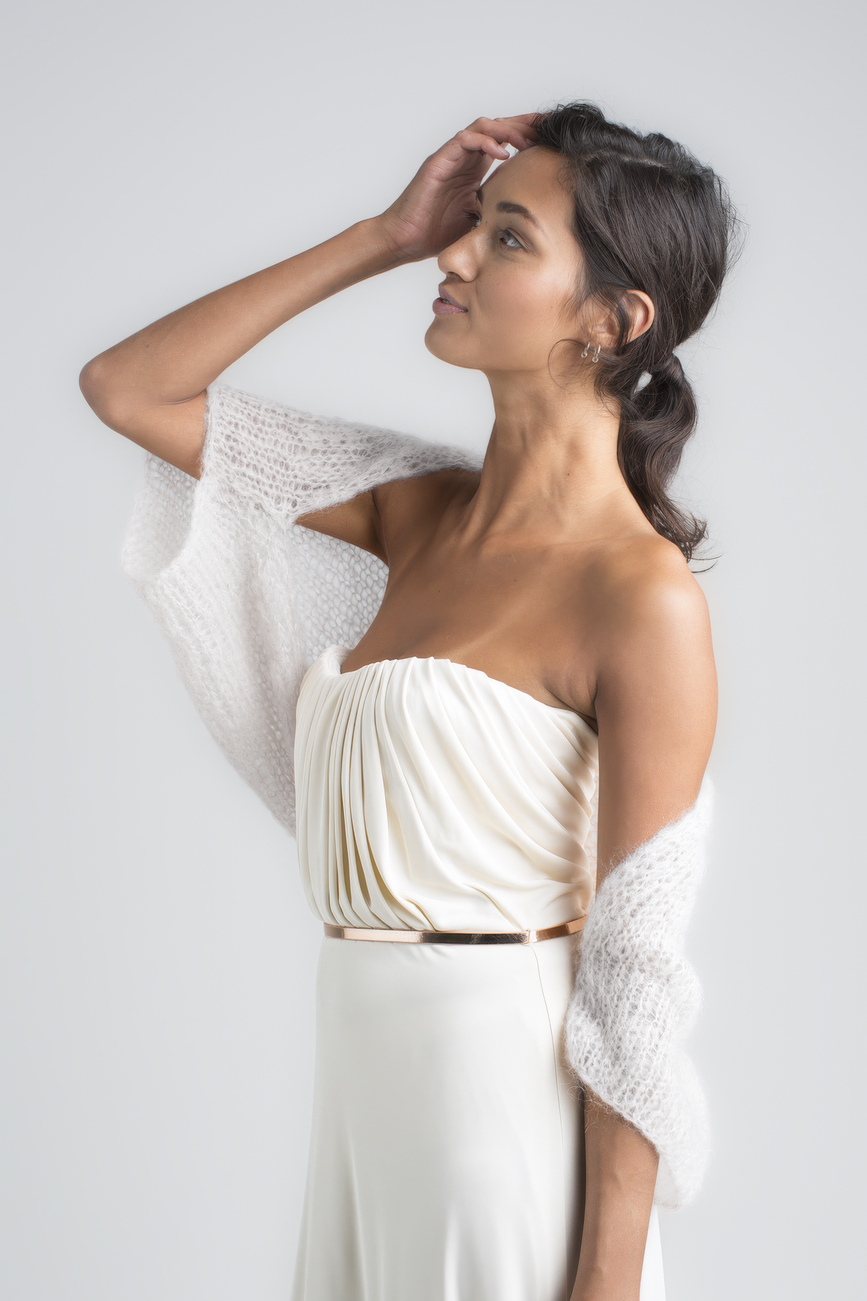 Braut trägt einen Ivory Bolero namens Endless Love und hält sich leicht am Kopf.