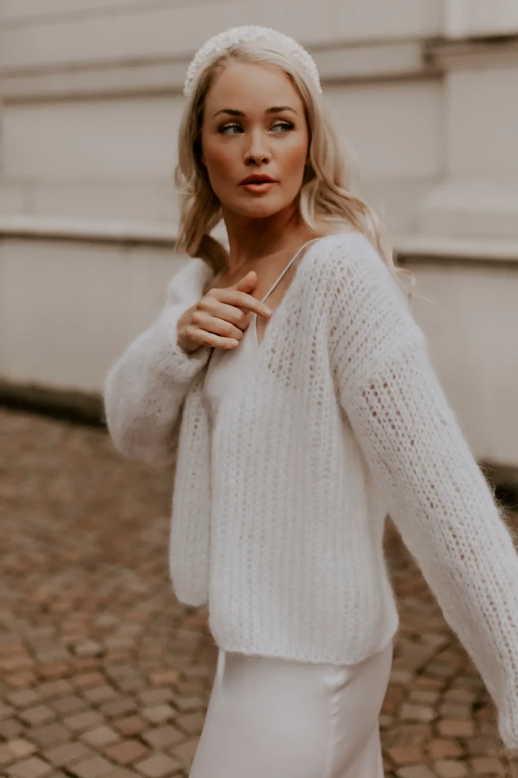 Eine Braut trägt den kuscheligen Brautcardigan FLUFFY FLEUR in der Farbe Ivory.