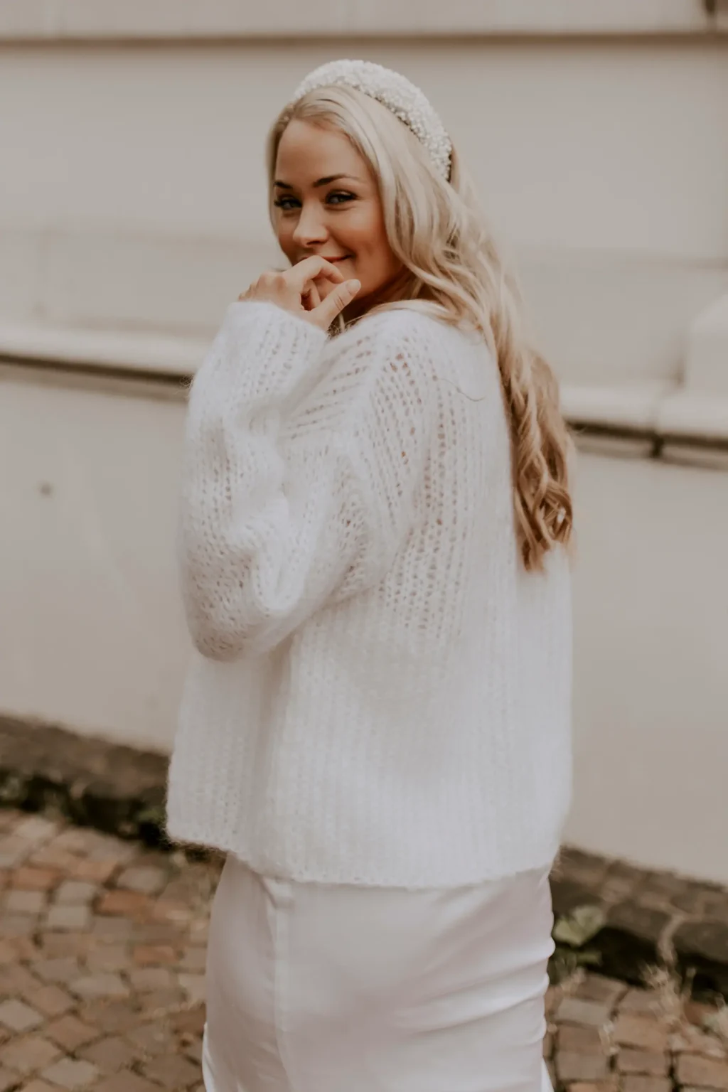 Eine Braut trägt den kuscheligen Brautcardigan FLUFFY FLEUR in der Farbe Ivory.