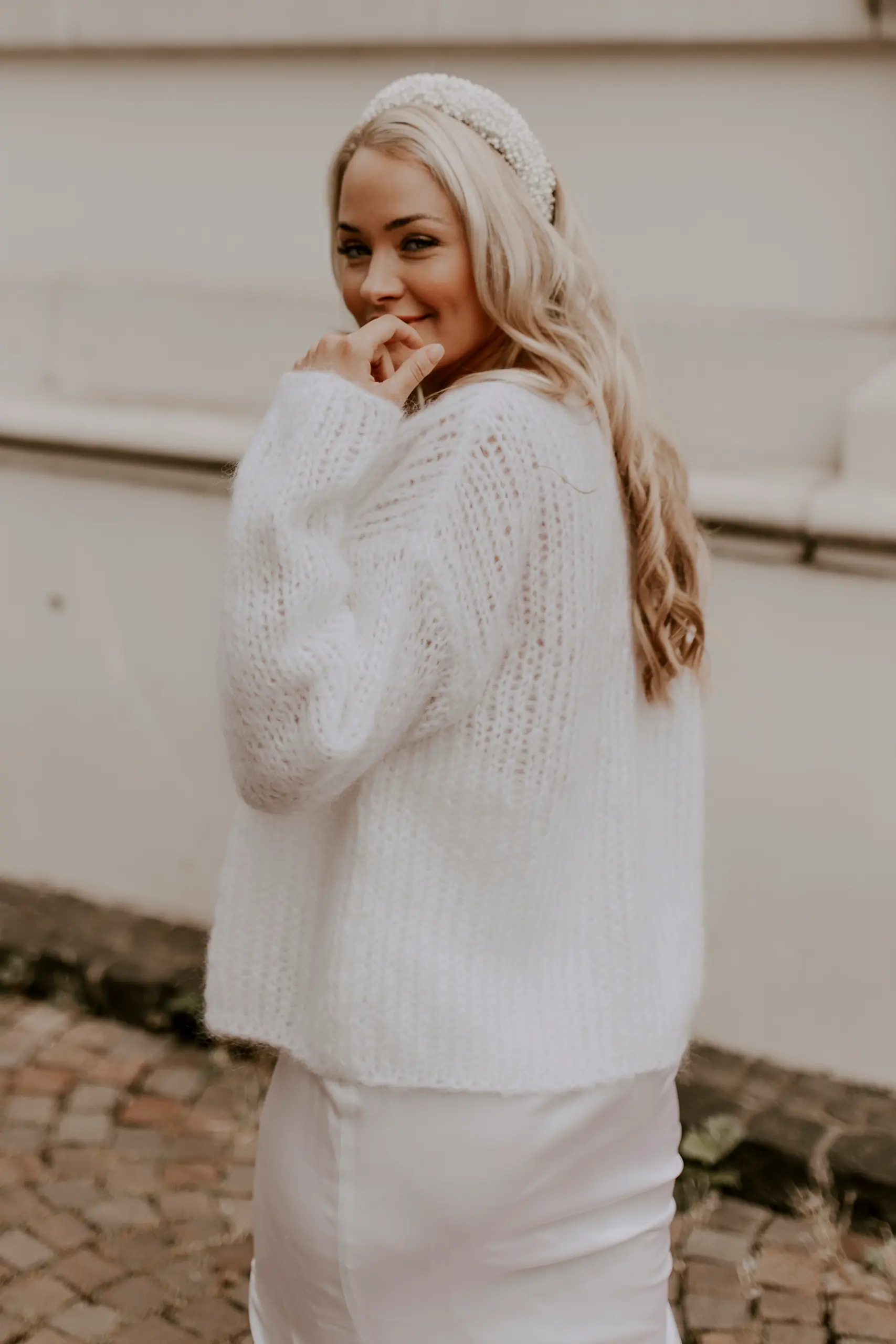 Eine Braut trägt den kuscheligen Brautcardigan FLUFFY FLEUR in der Farbe Ivory.