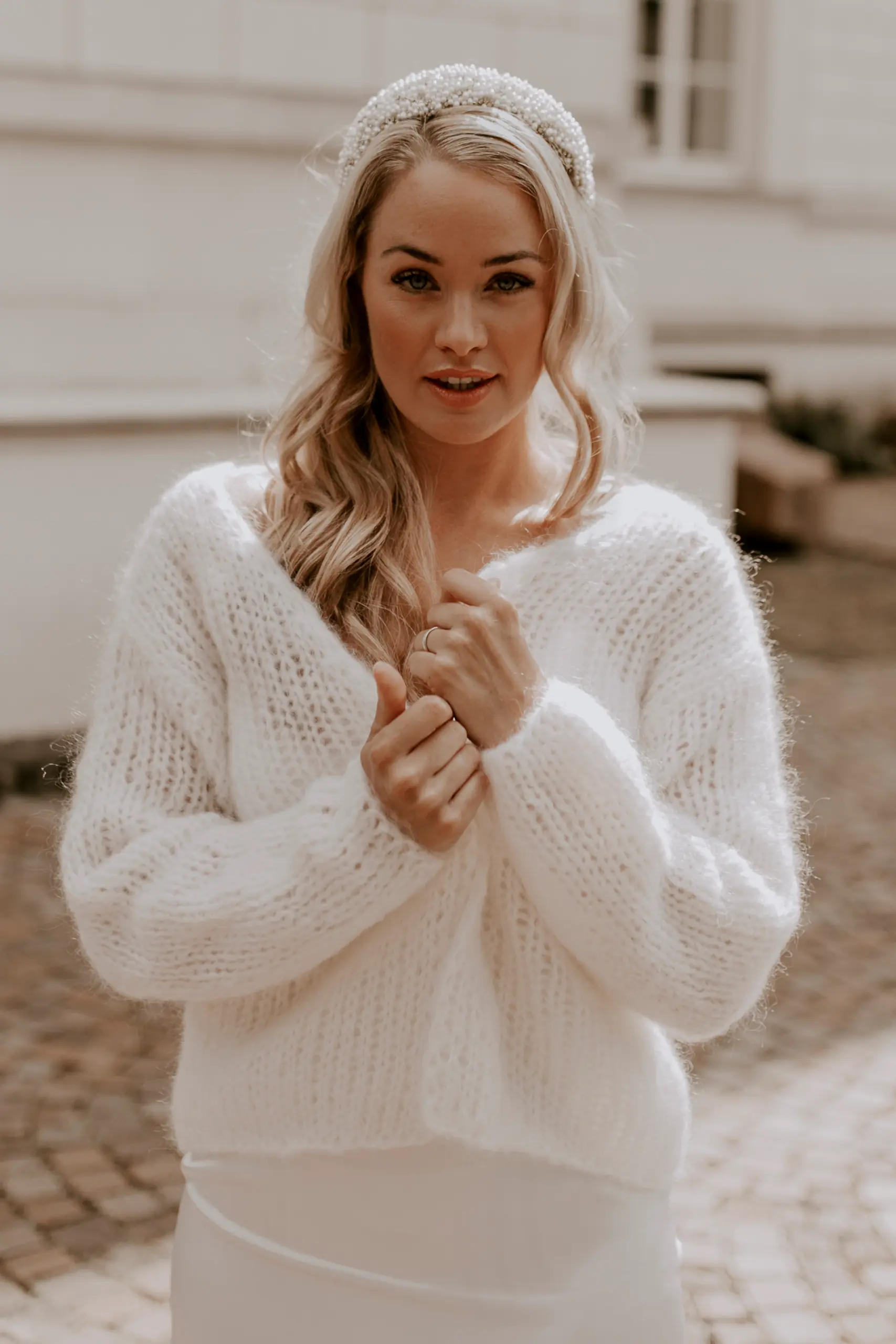 Eine Braut trägt den kuscheligen Brautcardigan FLUFFY FLEUR in der Farbe Ivory.