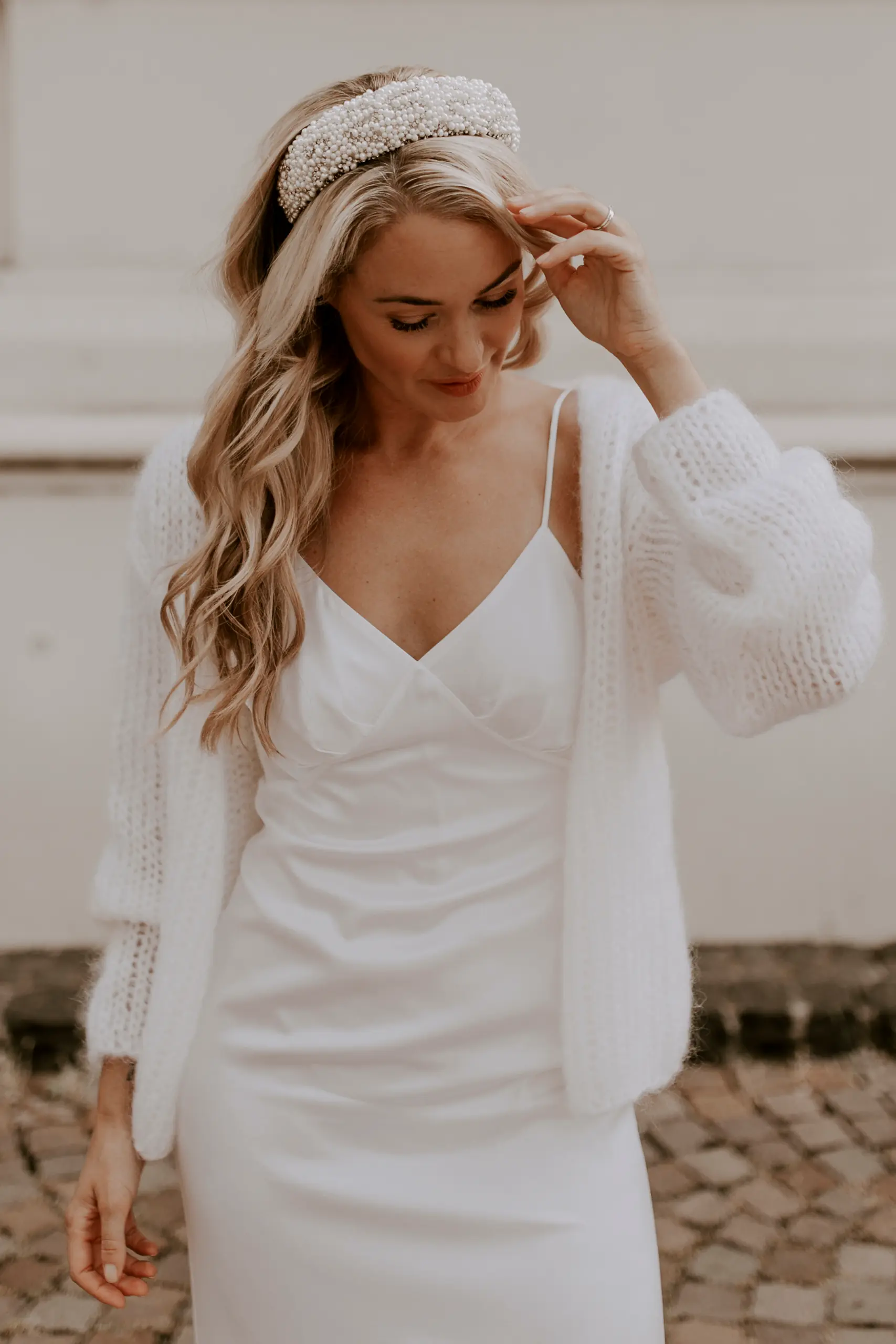 Eine Braut trägt den kuscheligen Brautcardigan FLUFFY FLEUR in der Farbe Ivory.